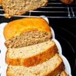 Slices-of-freshly-baked-homemade-banana bread-on-a-white-plate-showing-the-fluffy-and-moist-texture-with-the-rest-of-the-loaf-cooling-on-a-wire-rack.