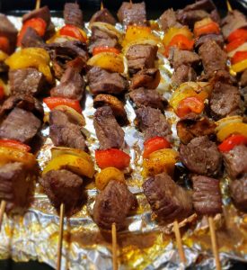 Close-up-of-juicy-grilled-beef-skewers-with-colorful-bell-peppers,-onions-and-mushrooms-resting-on-a-platter