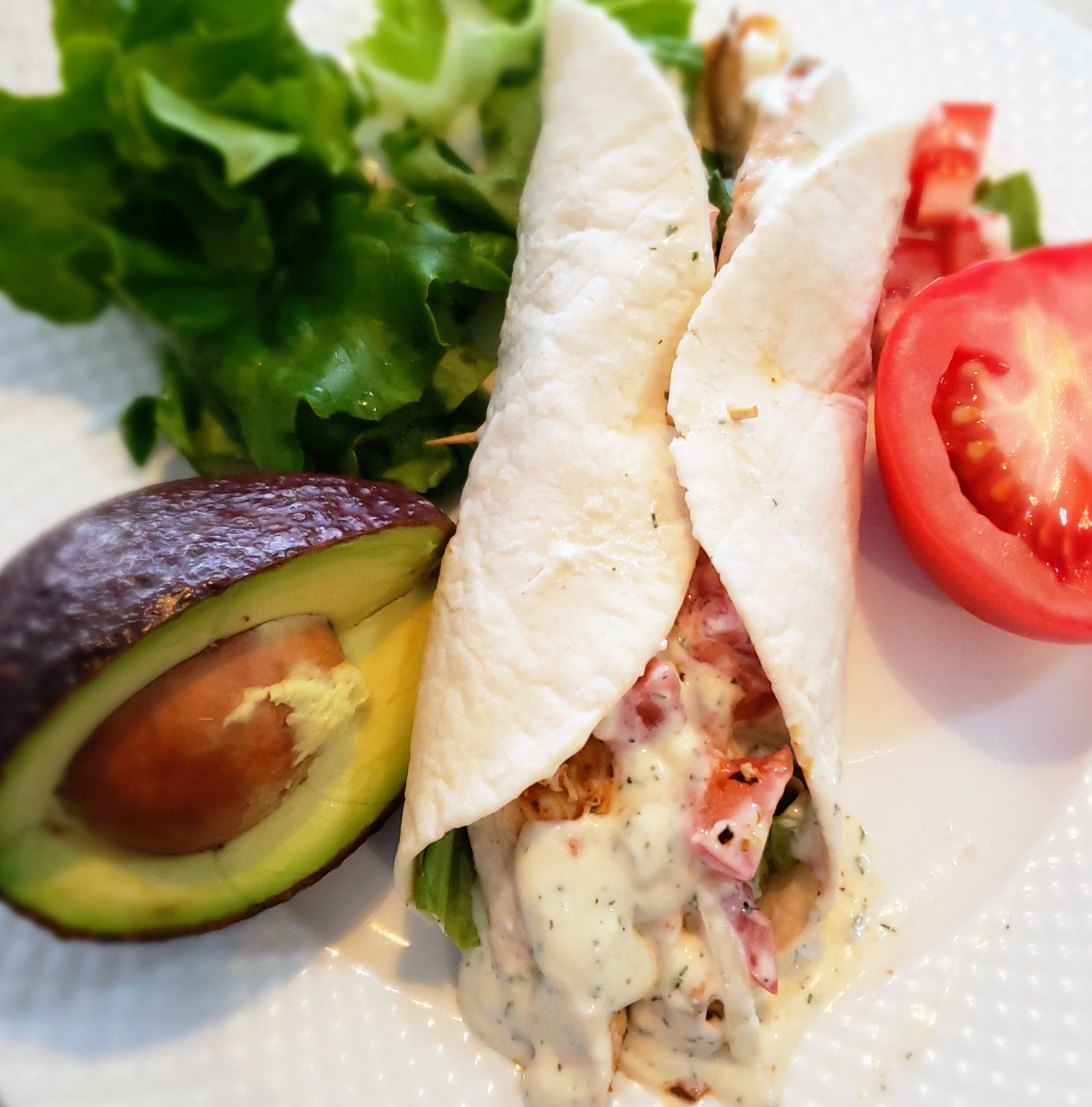 a-freshly-made-easy-chicken-wrap-sliced-in-half-showing-grilled-chicken-crisp-lettuce-tomatoes-and-creamy-sauce-inside.