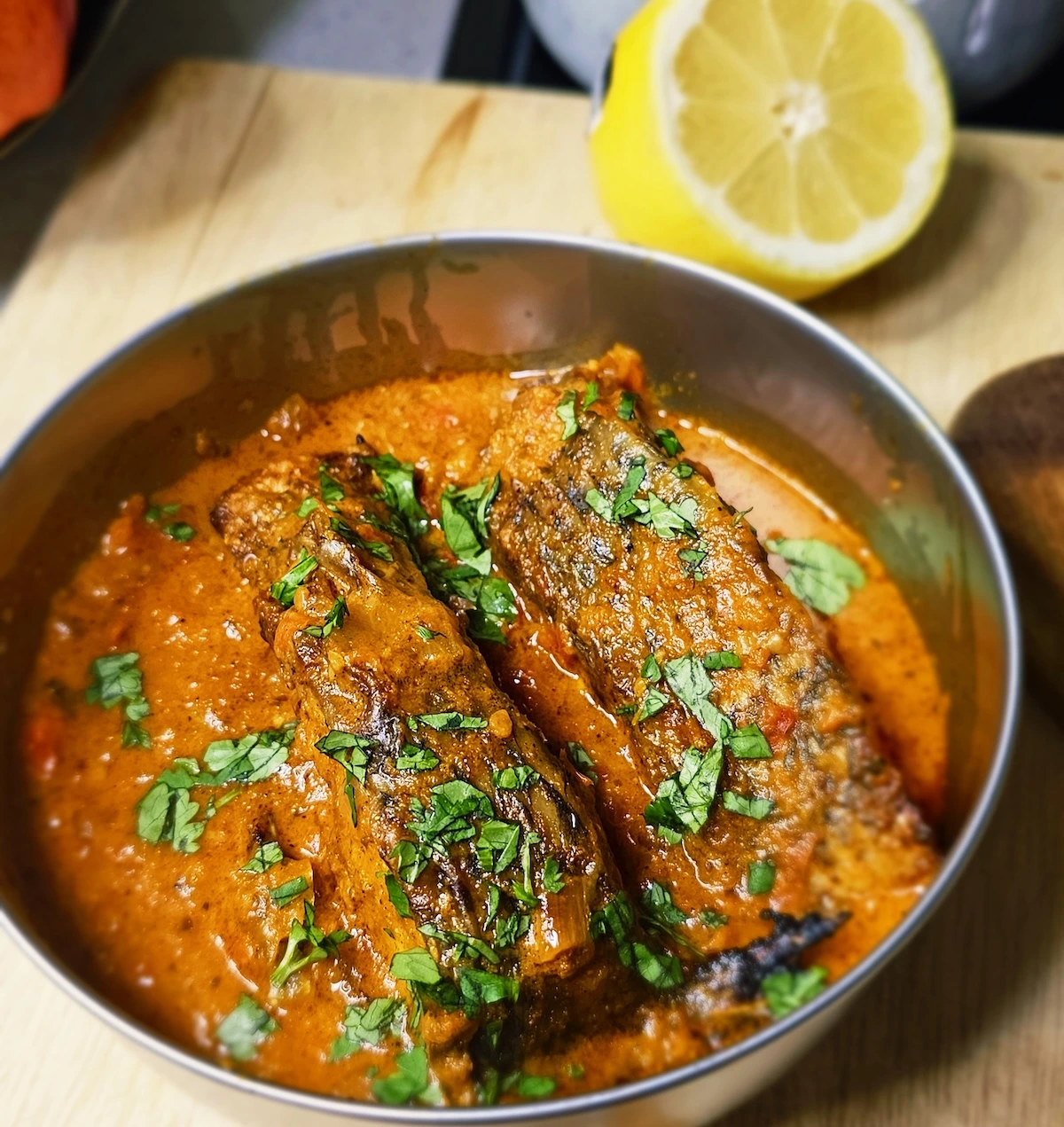Close-up-of-vibrant-fish-curry-with-air-fried-tilapia-pieces-in-a-creamy-tomato-coconut-sauce-garnished-with-fresh-cilantro.