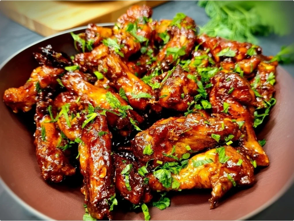 A-platter-of-crispy-baked-sticky-soy ginger chicken wings,-glistening-with-a-sweet-and-savory-glaze-and-garnished-with-sesame-seeds-and-sliced-green-onions