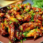 A-platter-of-crispy-baked-sticky-soy ginger chicken wings,-glistening-with-a-sweet-and-savory-glaze-and-garnished-with-sesame-seeds-and-sliced-green-onions