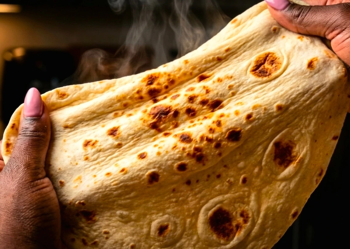 A-stack-of-soft,-flexible-homemade-shawarma-wrap-breads-wrapped-in-a-clean-white-kitchen-towel-to-maintain-steam.